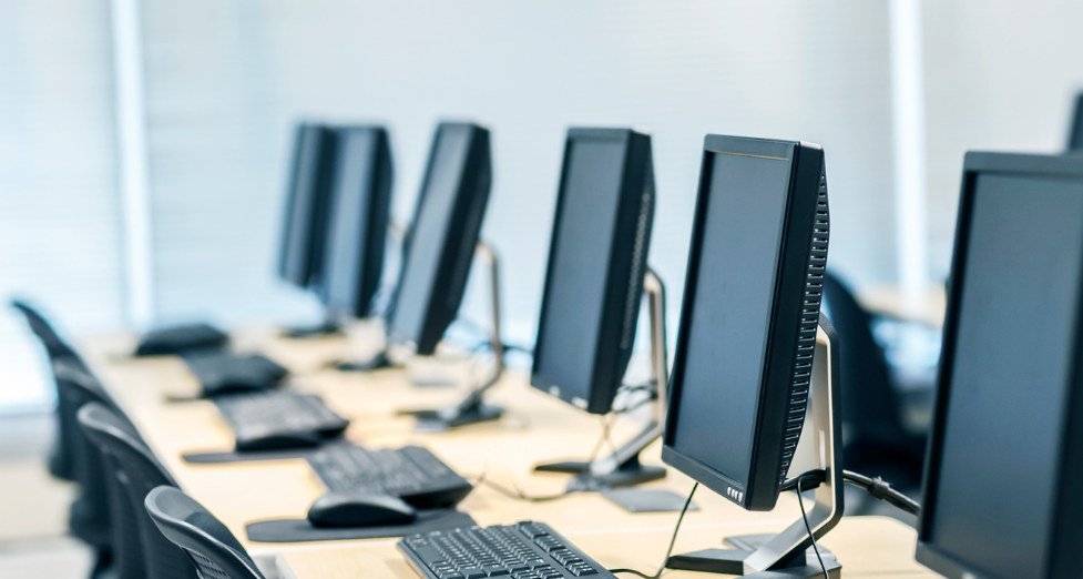 Computer equipment lined up on desks in a row