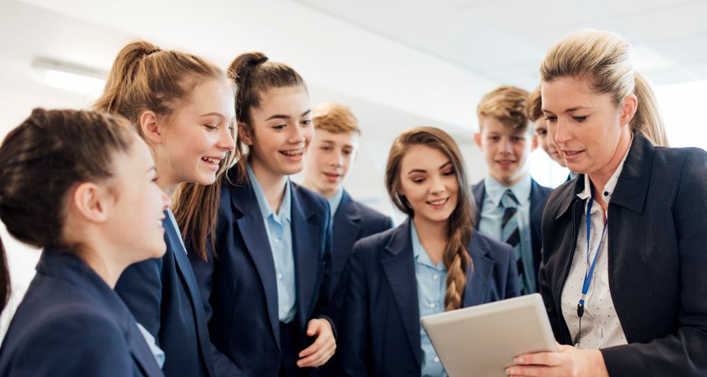 Teacher showing students something on an ipad in school classroom